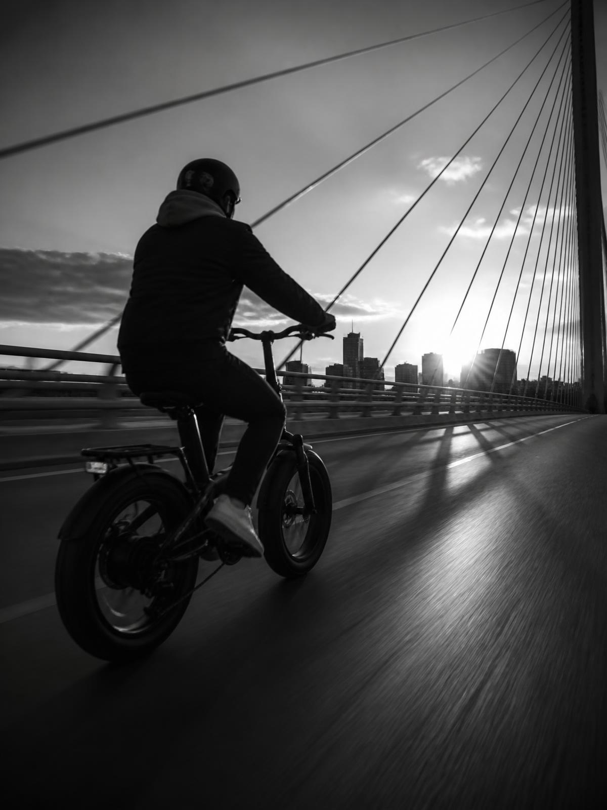 Rider crossing a modern bridge at sunset on a KOGO e-bike